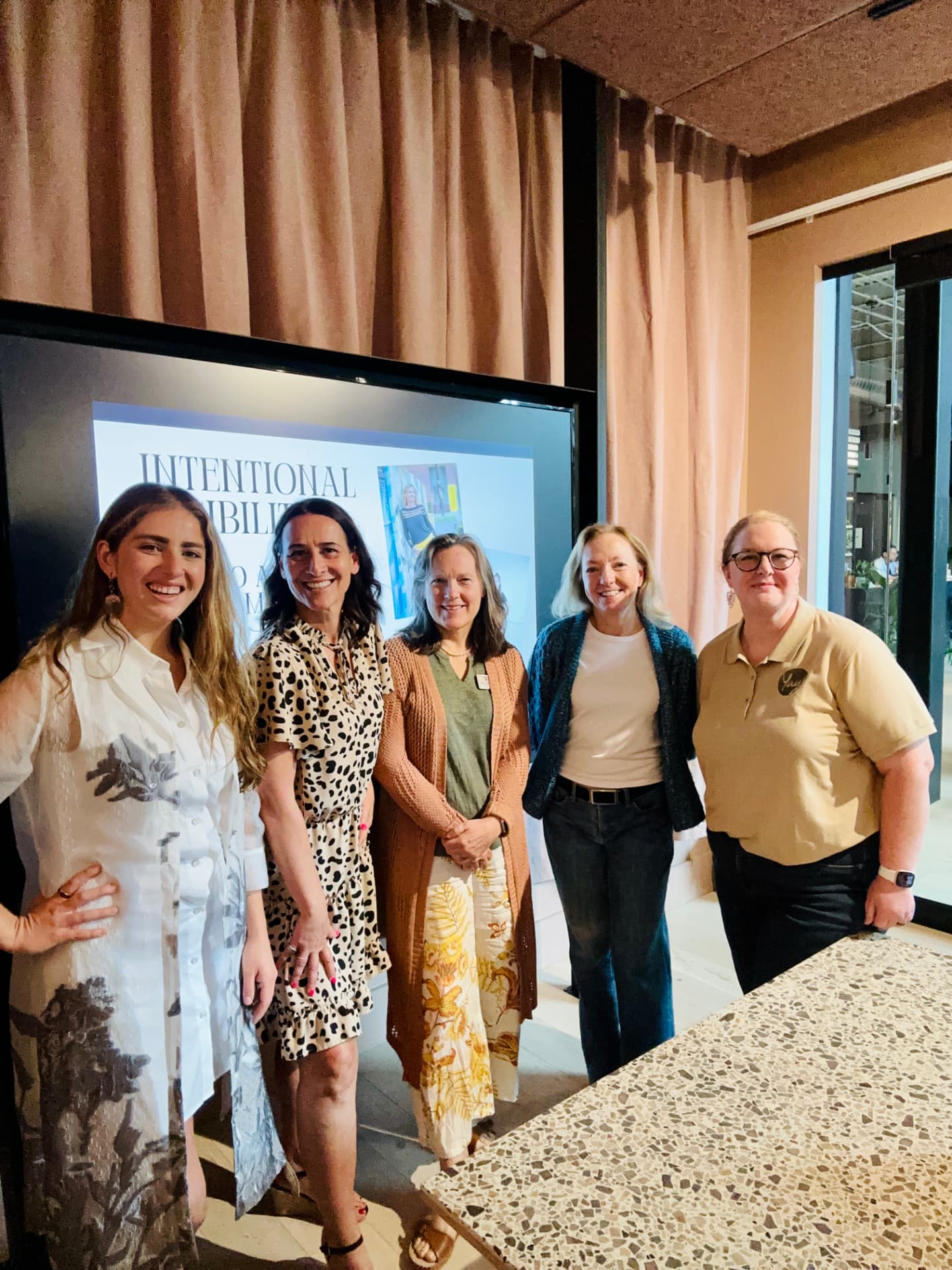 Emma and Monika with workshop attendees in front of the Intentional Visibility presentation screen
